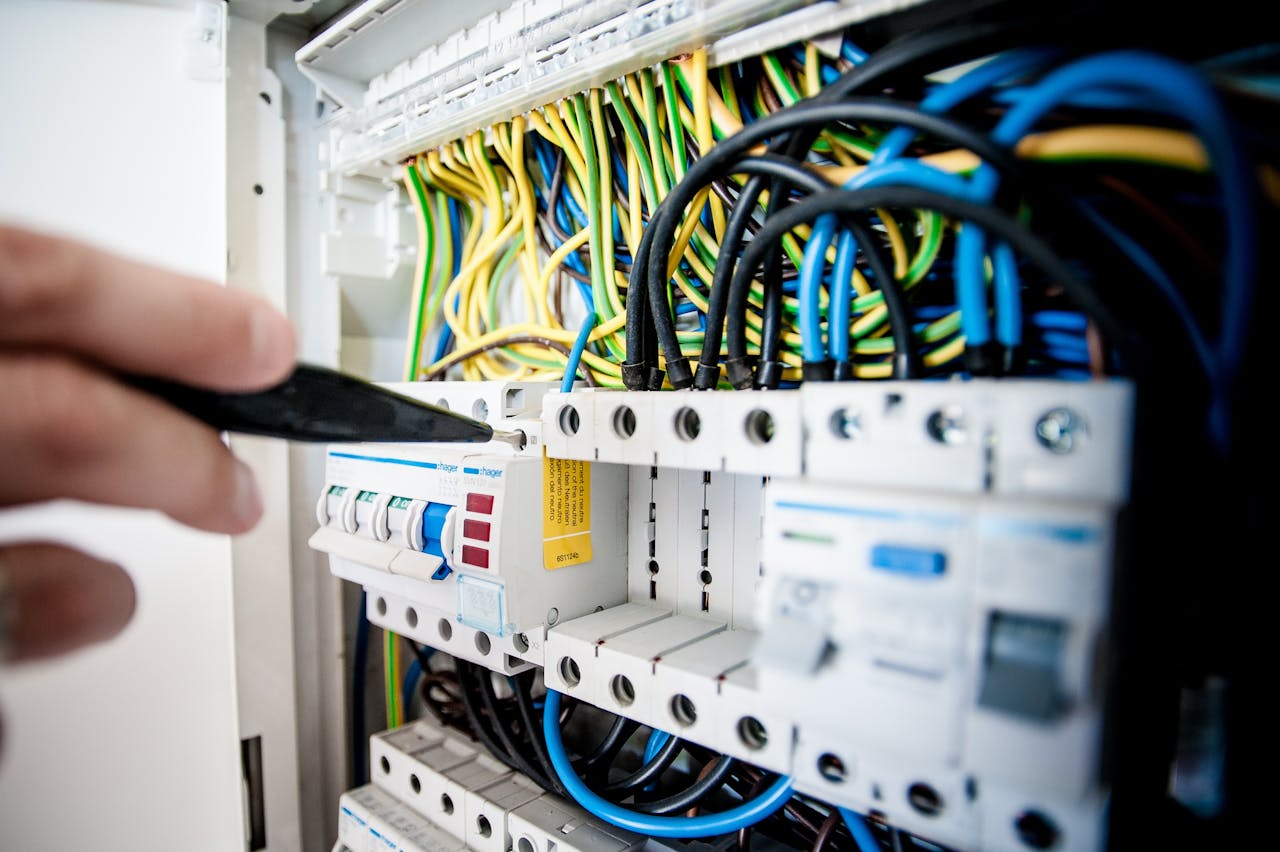 our-story Hand of electrician working on a circuit breaker panel with colorful wires, ensuring safe electrical connections.